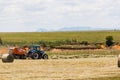 A tractor sorts hay and piles it into bales on a farm on KZN, South Africa.