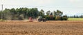 Tractor sowing on empty field, small trees in background. Wide agriculture banner