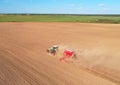 Field cultivating, aerial view. Tractor with disk harrow on plowed. Arable land ploughed and soil Tillage.