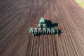 Tractor sows plowed soil on farm field, spring agriculture, aerial view from drone Royalty Free Stock Photo