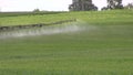 Tractor spray field with chemical pesticide in summer