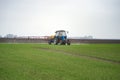 Tractor spraying agrochemical or agrichemical over young grain f