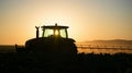 Tractor spraying crops at sunrise in cultivated field Royalty Free Stock Photo