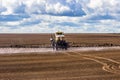 Tractor spraying a field on farm, fertilizes the land.