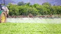 Tractor spraying pesticide, pesticides or insecticide spray on lettuce or iceberg field. Close-up view of pesticide machinary on