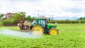 Tractor spraying pesticide, pesticides or insecticide spray on lettuce or iceberg field at sunset. Pesticides and insecticides on