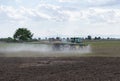 Tractor spraying pesticides on field with sprayer. Farmer fertilizes plants.