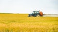 A tractor spraying water or fertilizer or chemical to golden barley field.