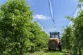 Tractor Sprays Pesticides in Apple Orchard in Springtime