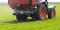 Tractor spreading artificial fertilizers in field