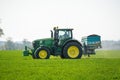 Tractor sprinkling fertiliser on wheat crop field. Hertfordshire. UK