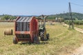 Tractor with straw baler next to a farm