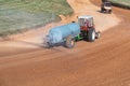 a tractor with a tank sprinkles water on the autocross track before the races