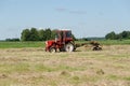 Tractor ted hay dry grass in agriculture field