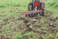 Tractor tilling the soil with vibrant green grass background