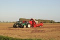 Two tractors with machines are harvesting onions in the fields in summer in holland