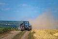 Tractor with a towed plow drives on dirt road between two fields