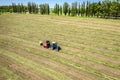 A tractor with a trailed bale making machine collects straw rolls in the field and makes round large bales Royalty Free Stock Photo