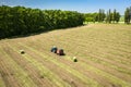 A tractor with a trailed bale making machine collects straw rolls in the field and makes round large bales Royalty Free Stock Photo