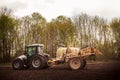 Tractor with trailer fertilizer-sprayer on ploughed field