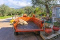 Tractor and trailer with olive rake and pruner parked in Greek village with olive groves on hillside behind