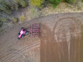 A tractor with a trailer plough plows a farmer\'s field from a aerial view. Top view of working rural machinery Royalty Free Stock Photo