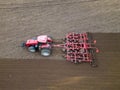 A tractor with a trailer plough plows a farmer\'s field from a aerial view. Top view of working rural machinery Royalty Free Stock Photo