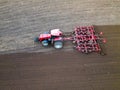 A tractor with a trailer plough plows a farmer\'s field from a aerial view. Top view of working rural machinery Royalty Free Stock Photo