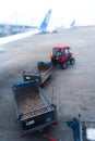 A tractor with a trailer for transporting passenger luggage between an airplane and an airport terminal. Baggage transportation