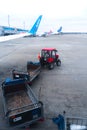 A tractor with a trailer for transporting passenger luggage between an airplane and an airport terminal. Baggage transportation