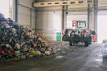 Tractor transports garbage at the plant for processing and sorting waste. Raised bulldozer bucket with waste. Pile of trash in the