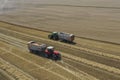 A tractor transports the ripe golden wheat to the grain field harvested by the combine. Agricultural work in summer. Drone