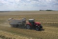 A tractor transports the ripe golden wheat to the grain field harvested by the combine. Agricultural work in summer. Drone