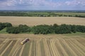 A tractor transports the ripe golden wheat to the grain field harvested by the combine. Agricultural work in summer. Drone