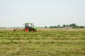 Tractor turning raking cut hay in field Royalty Free Stock Photo