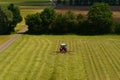 Tractor turns over freshly cut hay for drying. Royalty Free Stock Photo