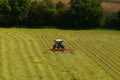 Tractor turns over freshly cut hay for drying. Royalty Free Stock Photo