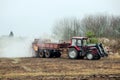 Tractor use manure much spreader trailer to scatter hot steaming horse manure on agriculture field