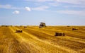 A tractor uses a trailed bale machine to collect straw in the field and make round large bales. Agricultural work, baling, baler, Royalty Free Stock Photo