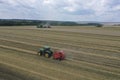 A tractor uses a trailed bale machine to collect straw in the field and make round large bales. Agricultural work, baling, baler,