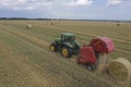 A tractor uses a trailed bale machine to collect straw in the field and make round large bales. Agricultural work, baling, baler,