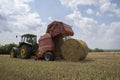 A tractor uses a trailed bale machine to collect straw in the field and make round large bales. Agricultural work, baling, baler, Royalty Free Stock Photo