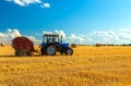 A tractor uses trailed bale machine to collect straw in the field and make round large bales. Agricultural work, baling Royalty Free Stock Photo