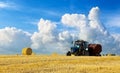 A tractor uses trailed bale machine to collect straw in the field and make round large bales. Agricultural work, baling Royalty Free Stock Photo