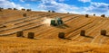 tractor uses a trailed bale machine to collect straw in the field and make round large bales. Agricultural work, hay collection