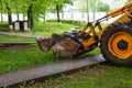 A tractor on wheels with a bucket on a city street performs