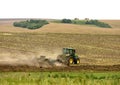 Tractor at work cultivating a field, farmland, plowed field,