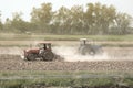 Tractor working in field opening preparing soil for planting rice.