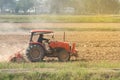 Tractor working in field opening preparing soil for planting rice.