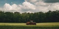 Tractor working in lush green field under dramatic cloudy sky Royalty Free Stock Photo